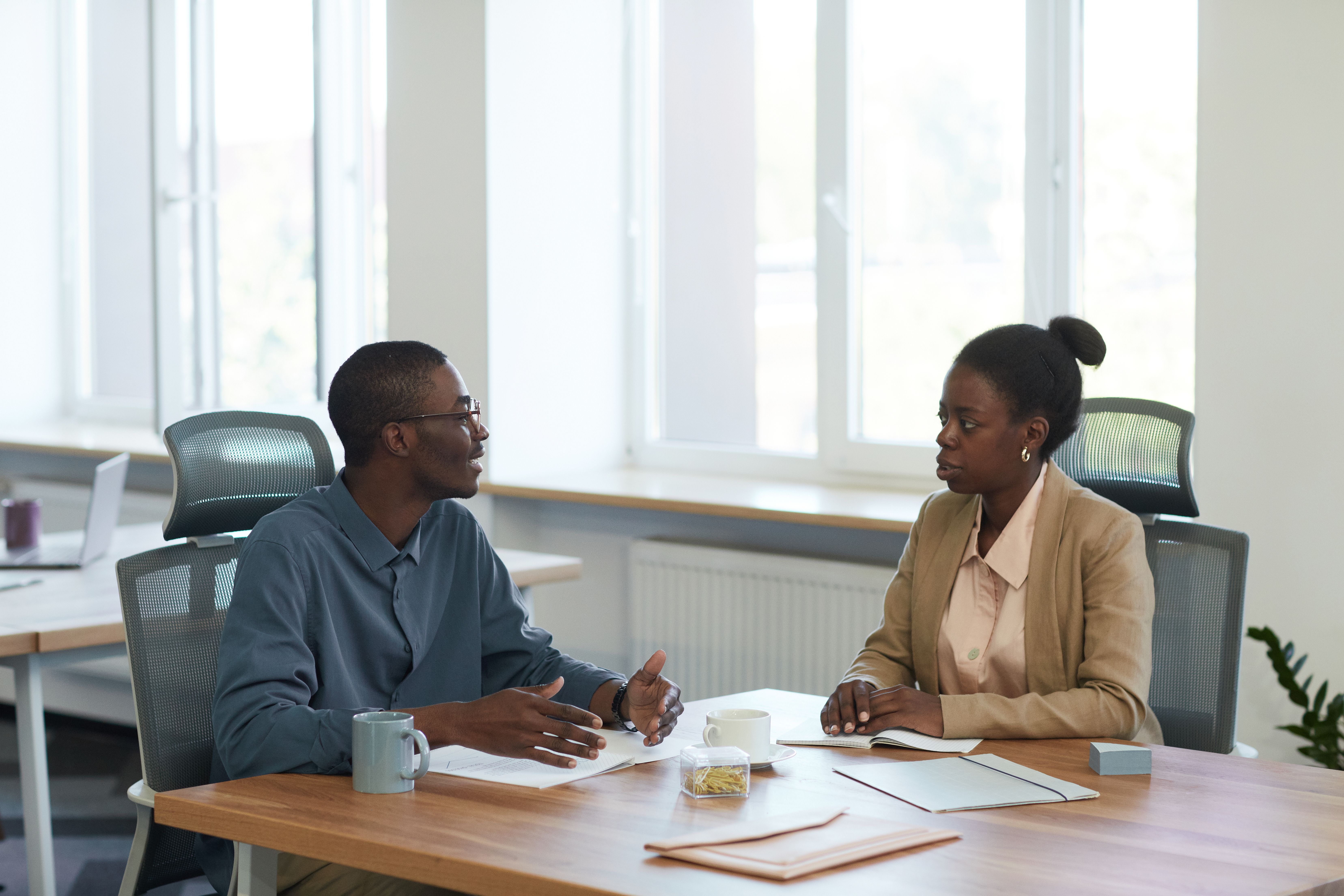 Two colleagues having a friendly business conversation in a modern office